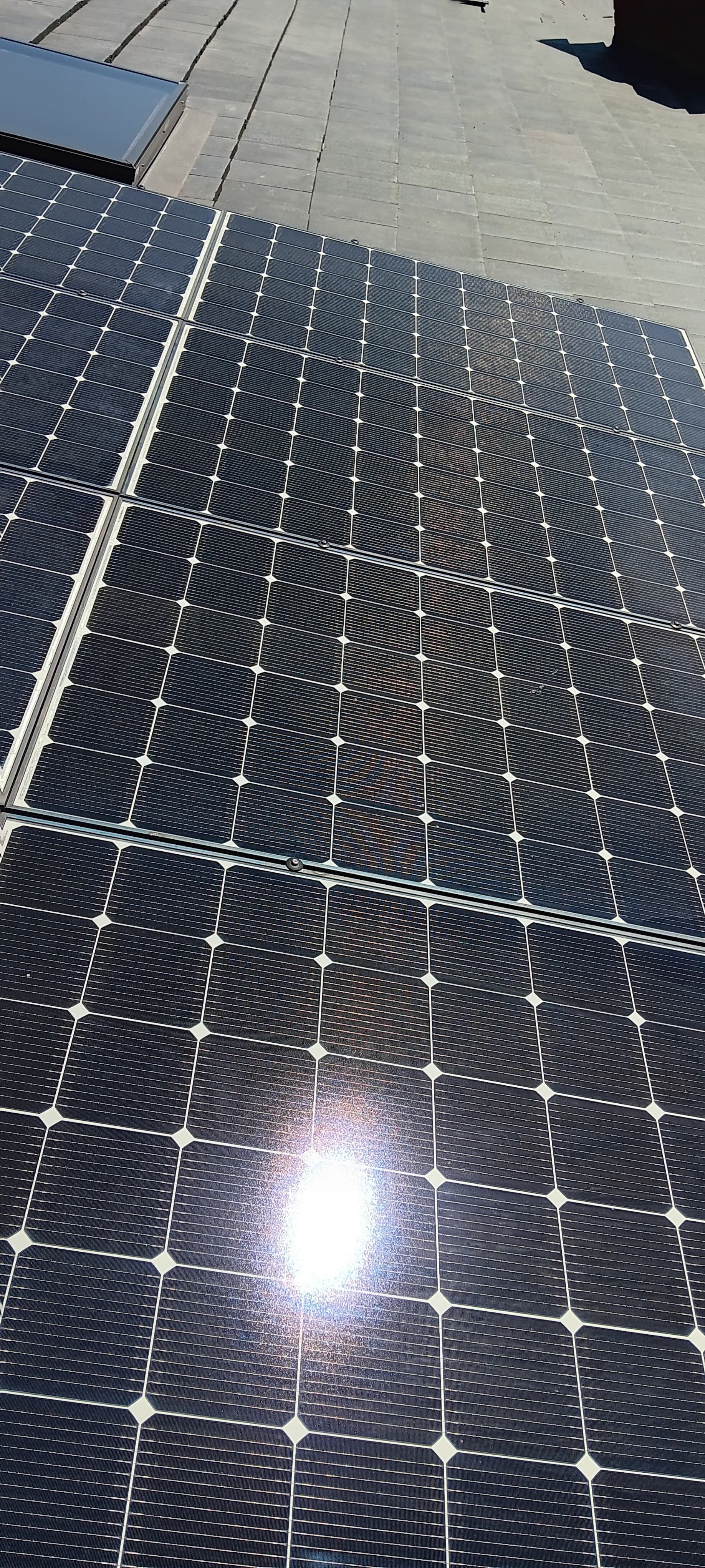 Solar panels on a rooftop, reflecting sunlight.