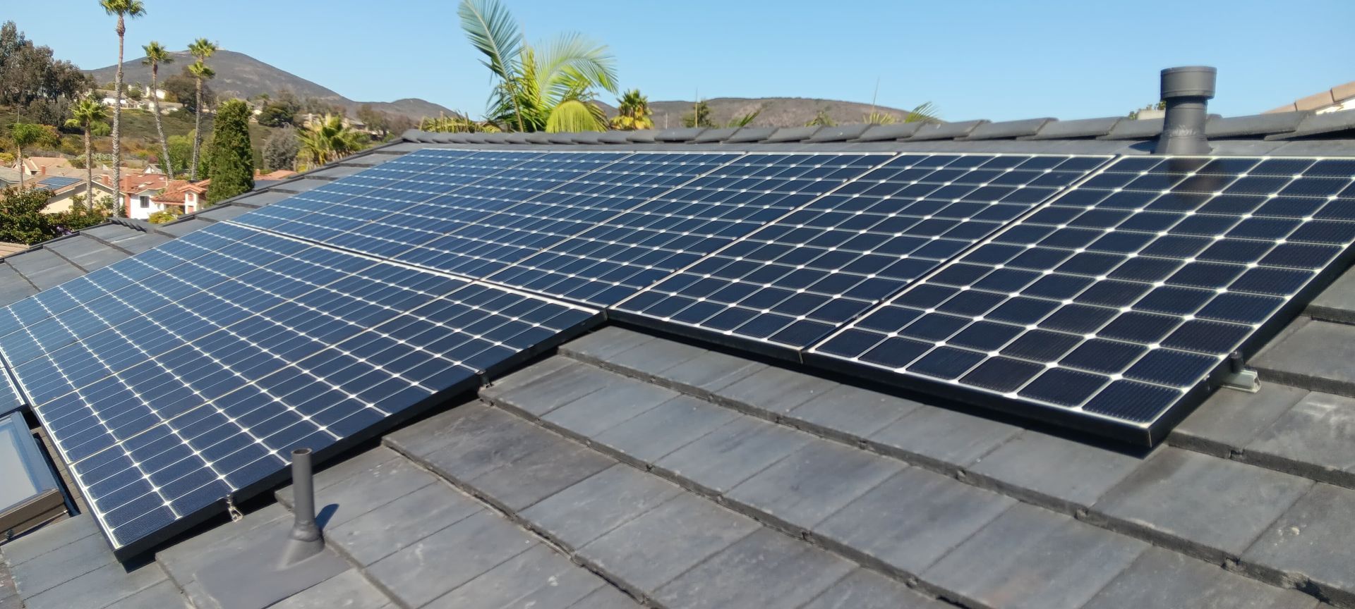 Solar panels installed on a tiled roof, with a blue sky in the background.