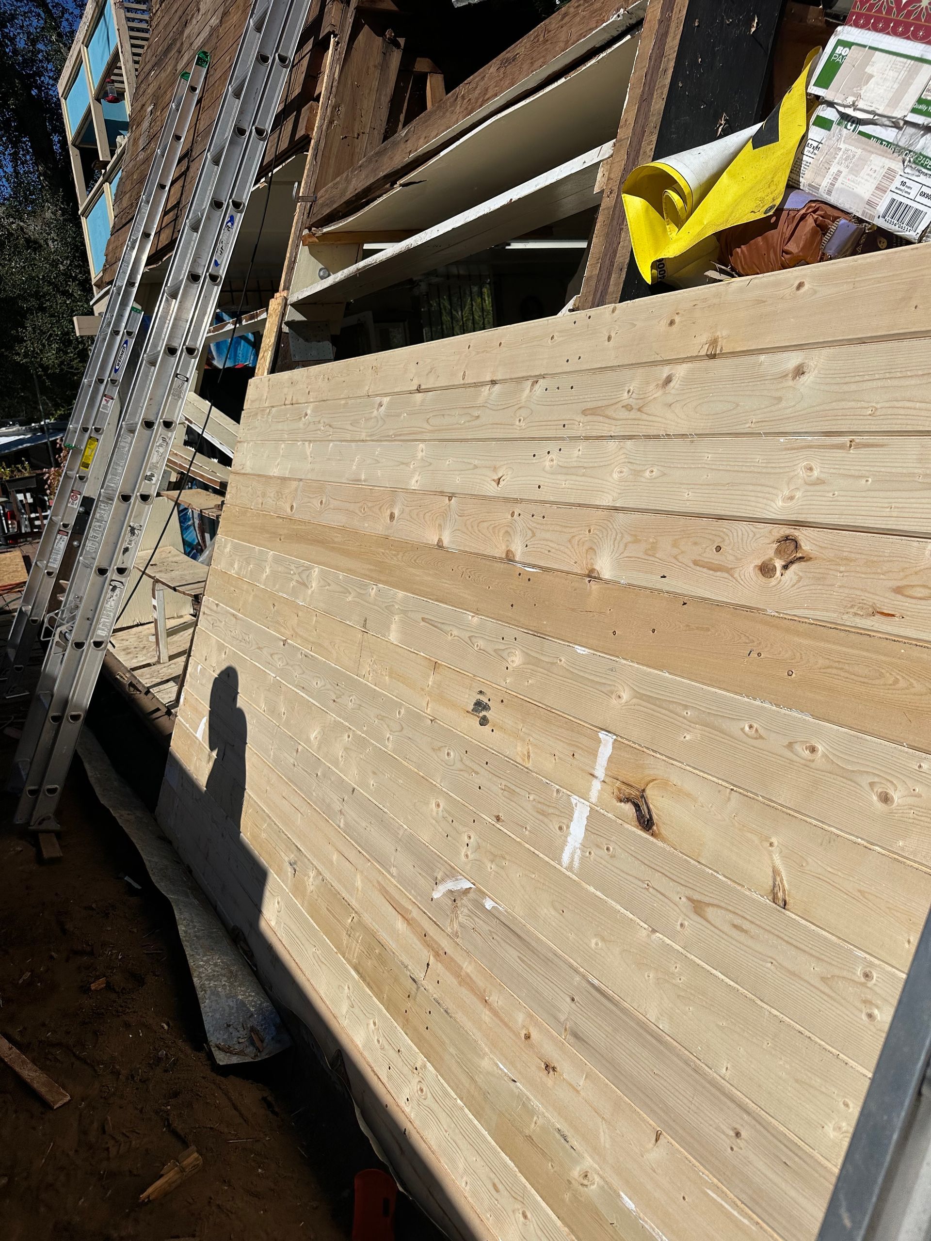 New wood siding on a house under construction; ladder and construction materials visible.