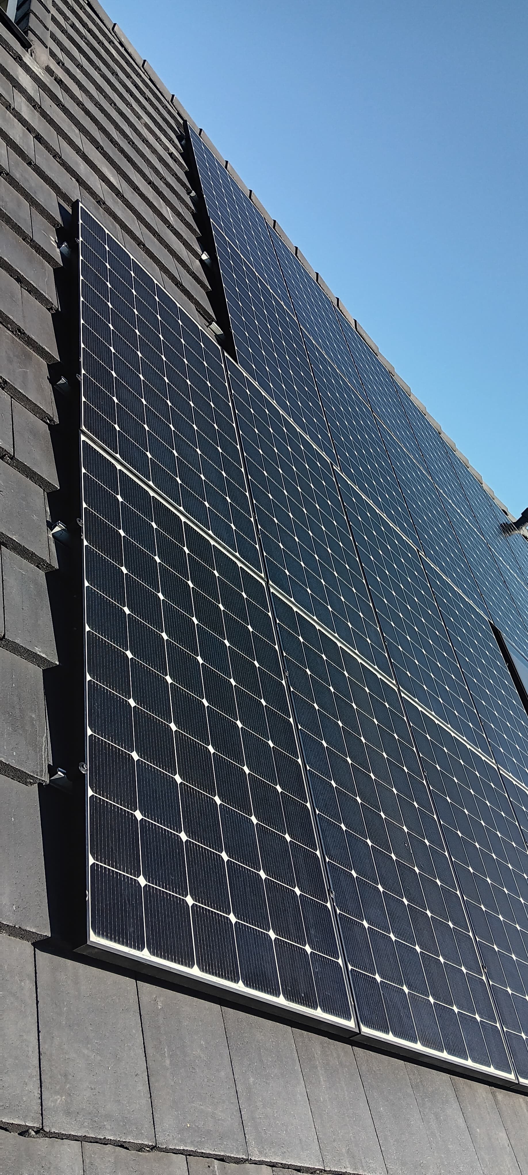 Solar panels installed on a roof against a blue sky.