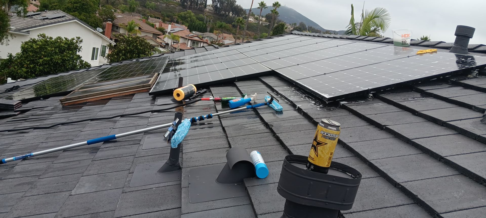 Solar panels being installed on a dark gray roof, with tools and equipment visible.