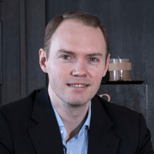 A man in a suit and blue shirt is smiling for the camera.