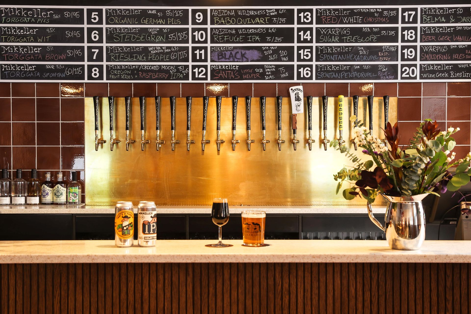 En bar med en masse ølhaner og en tavle på væggen.