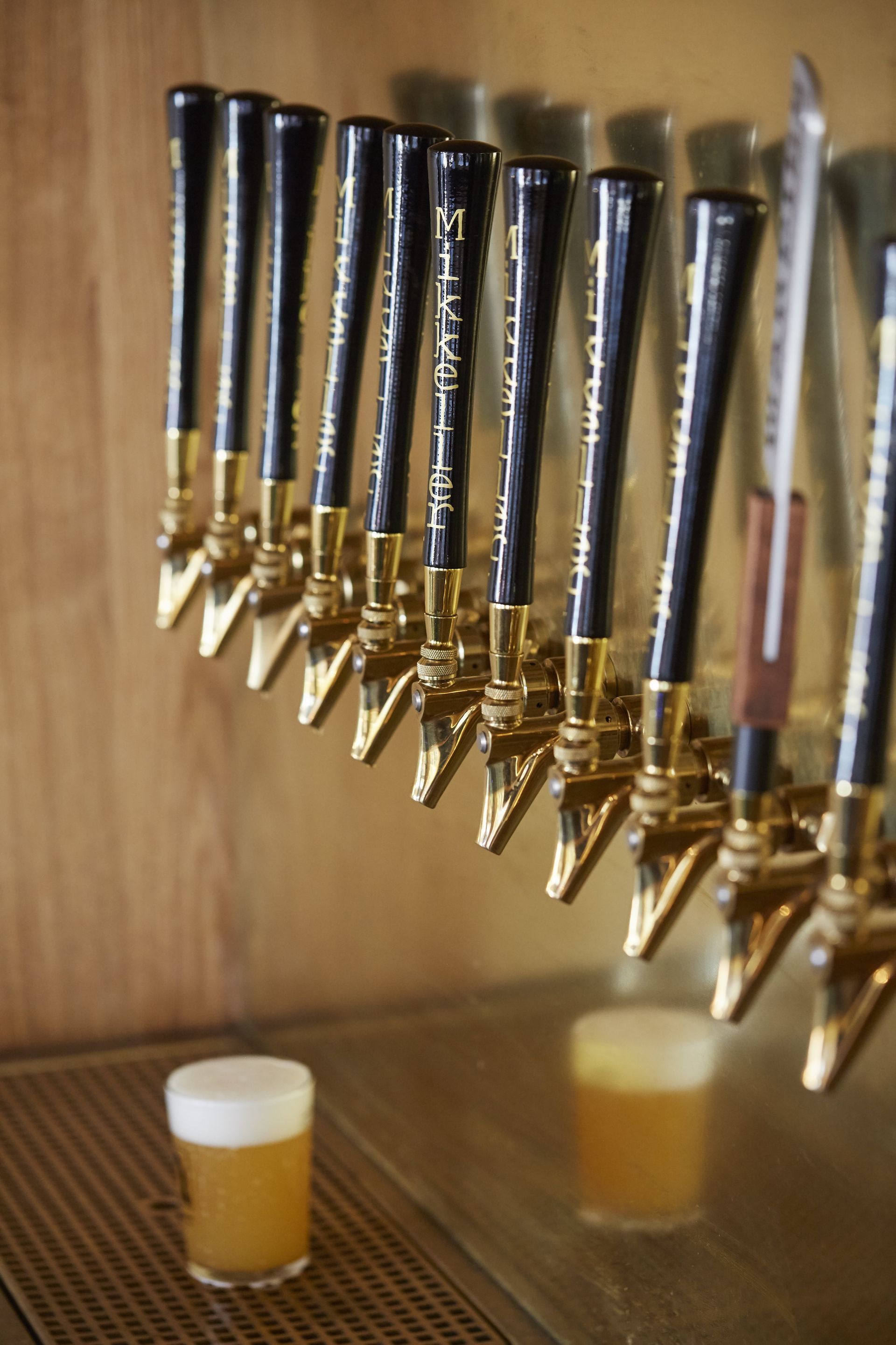 En række ølhaner med et glas øl foran