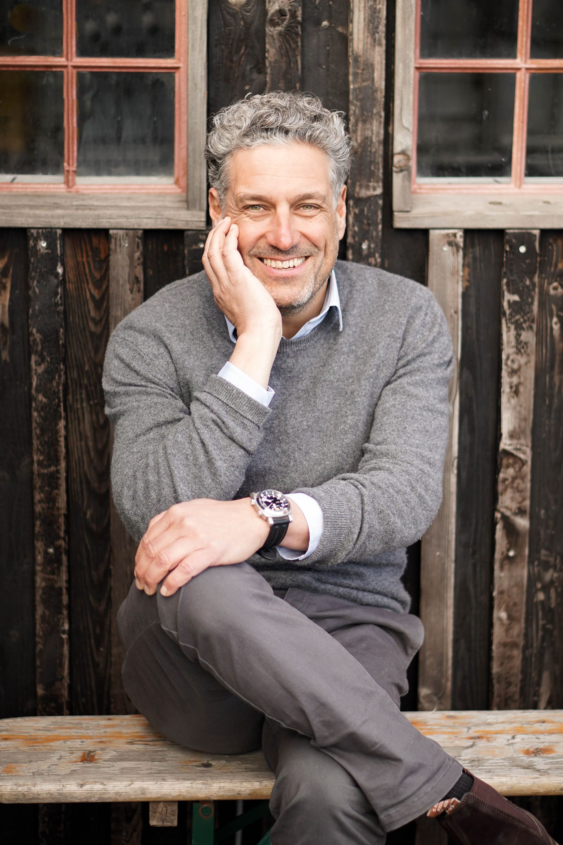 En mand sidder på en bænk med hånden på hagen.