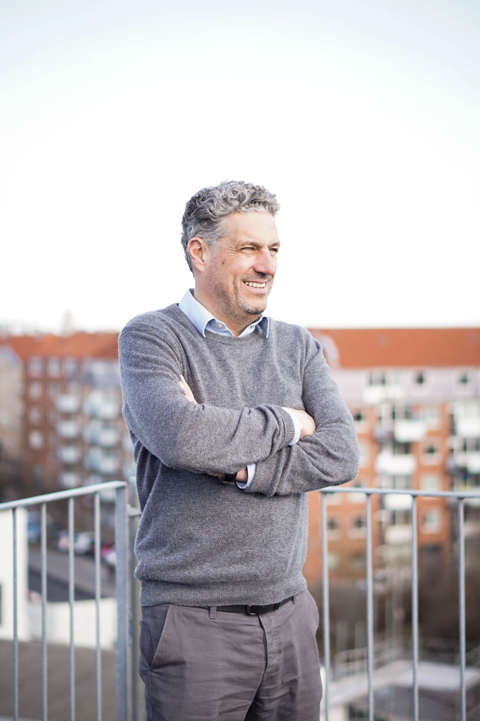 En mand står på en balkon med armene over kors.