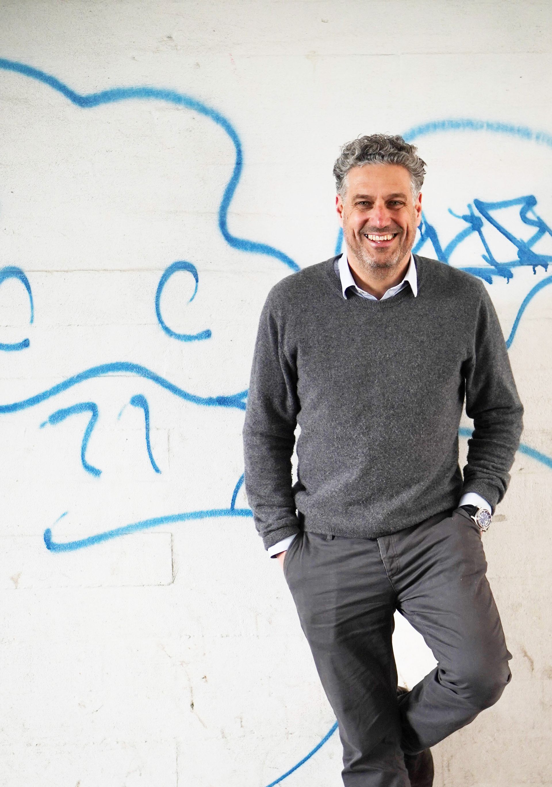 En mand står foran en væg med graffiti på.