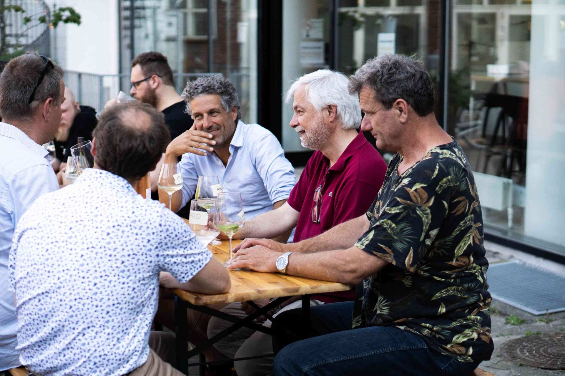 En gruppe mænd sidder ved et bord og taler med hinanden.