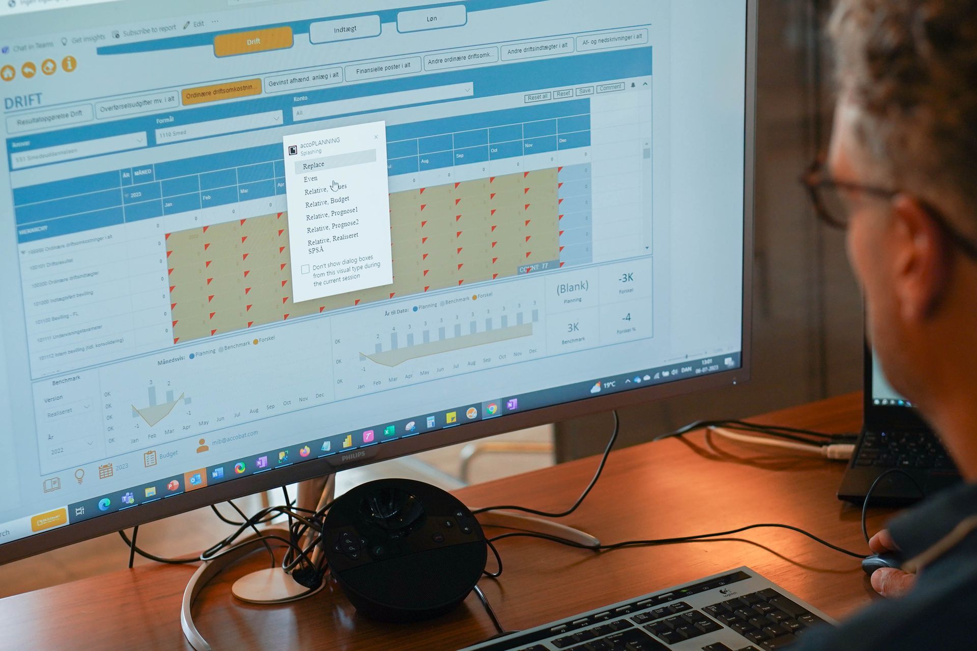 En mand sidder ved et skrivebord og ser på en computerskærm.