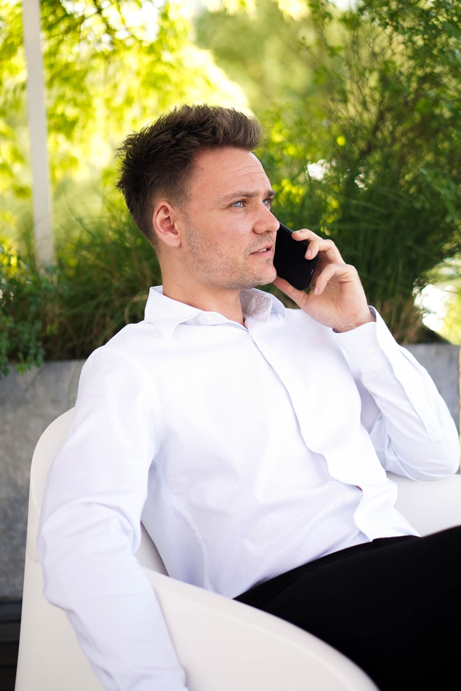 En mand sidder i en stol og taler i en mobiltelefon.