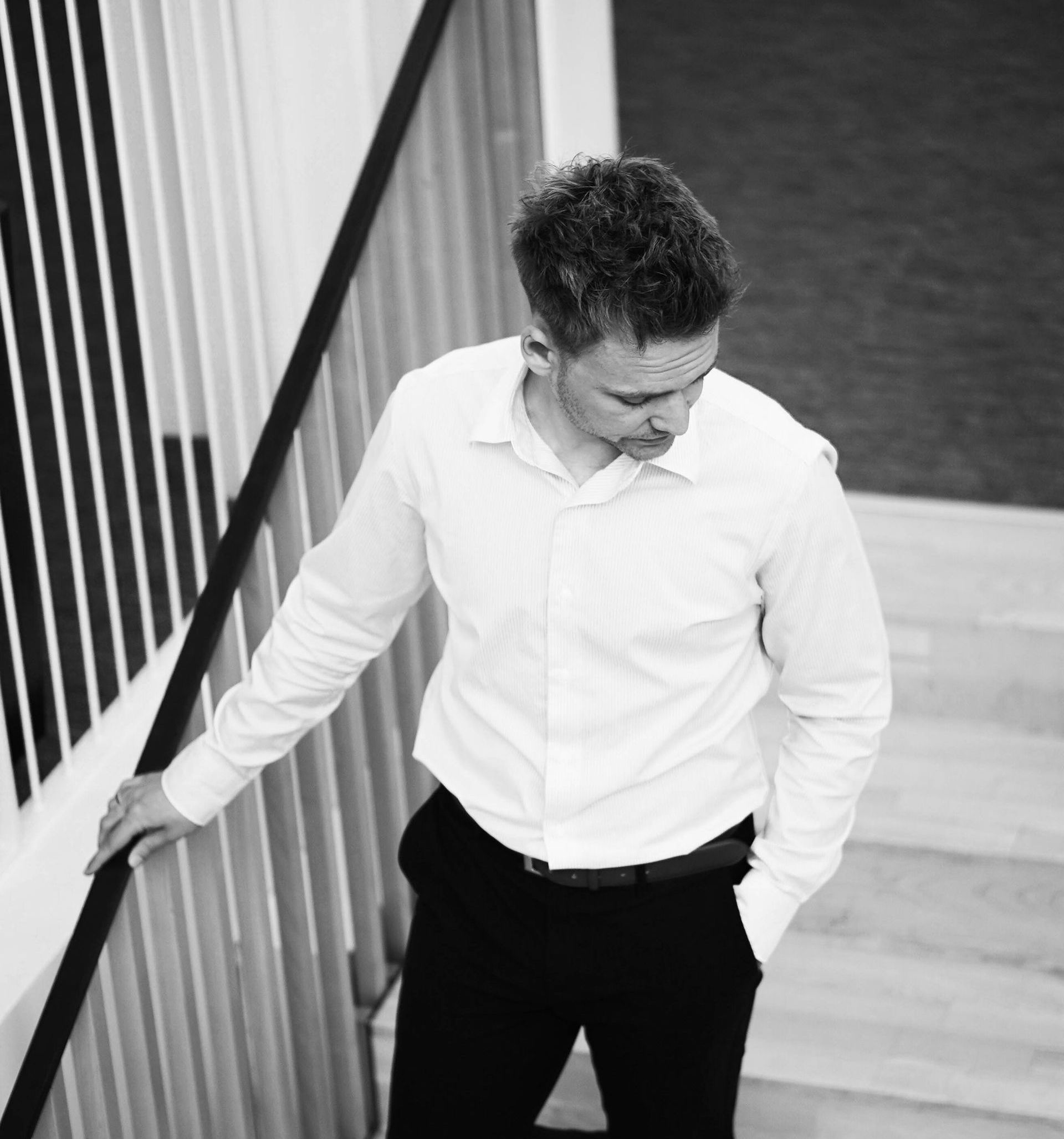 En Business Intelligence ekspert i hvid skjorte læner sig op ad et rækværk på en trappe