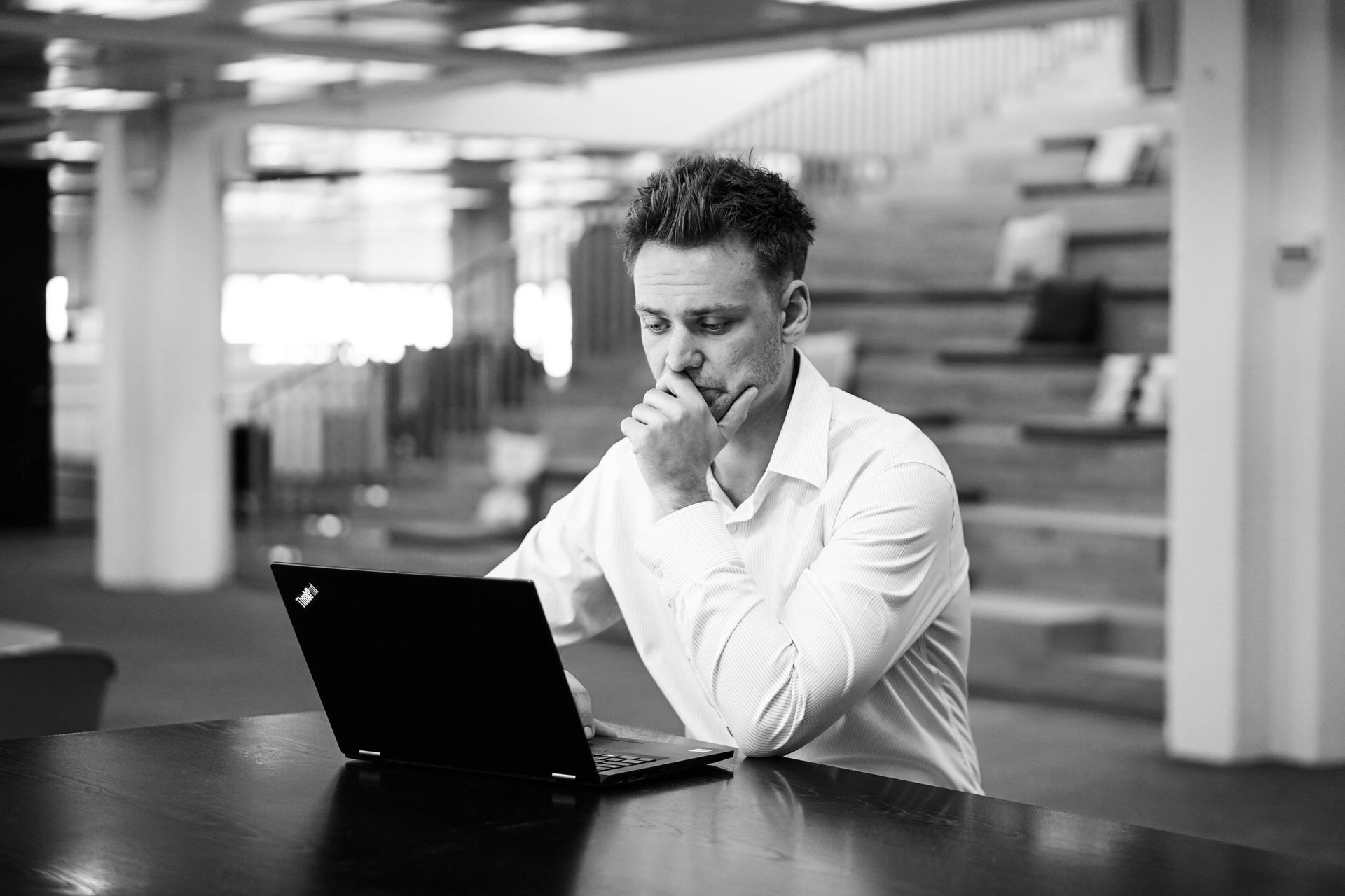 En Business Intelligence konsulent sidder ved et bord og ser på en bærbar computer.