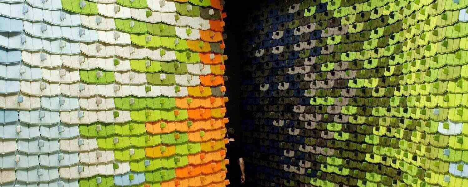 A person is standing in front of a wall made of sticky notes.
