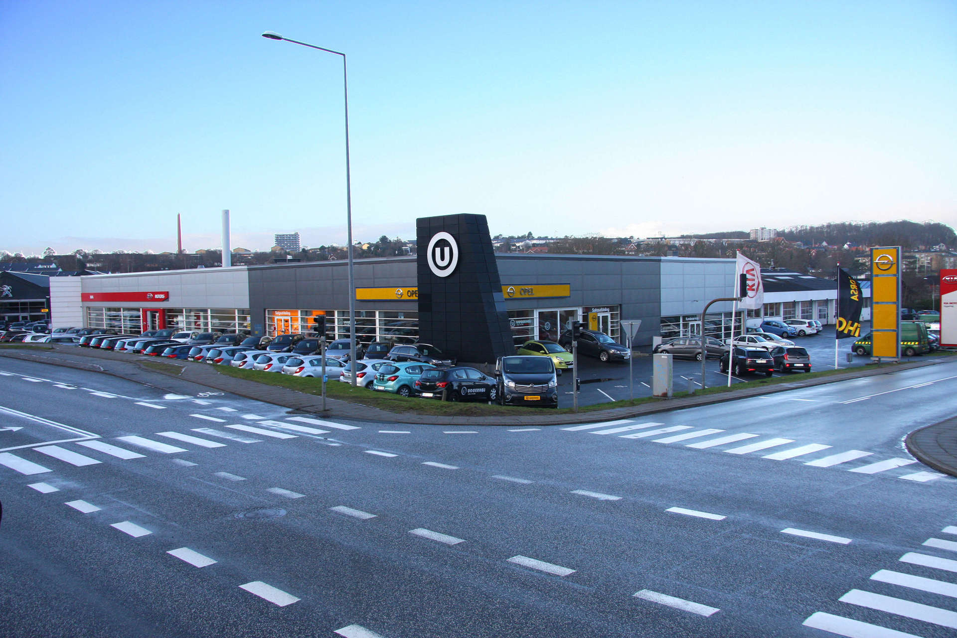 A lot of cars are parked in front of a building with the letter u on it