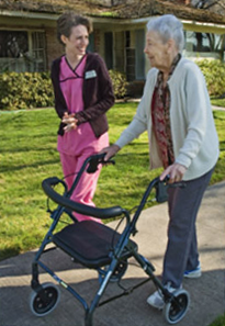 A female caregiver walking with an elderly patient.