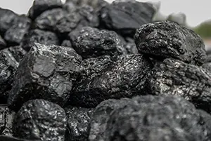 A close-up pile of rough, black, shiny lumps of coal.