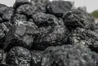 A close-up pile of rough, black, shiny lumps of coal.