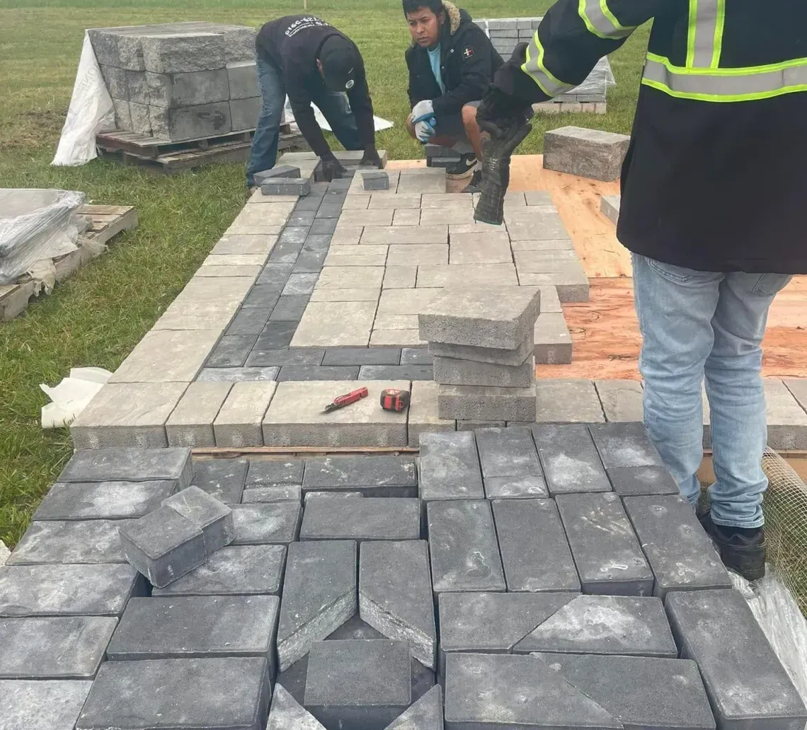 Stacked gray concrete cinder blocks on wooden pallets outdoors under a clear blue sky.