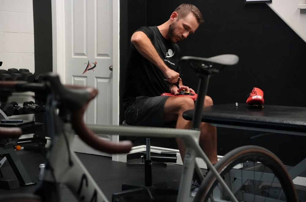 Image of Dr. Peter Lejkowski, professional bike fitter, adjusting the cleat on a cycling shoe to help a cyclist with foot pain and numbness