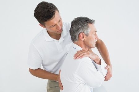 a man is giving an older man a massage on his back .