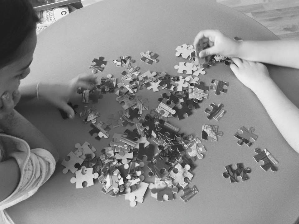 una bambina e una mano davanti a dei pezzi di puzzle
