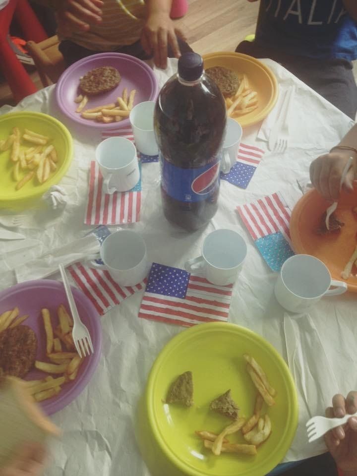 dei piatti colorati con patatine, hamburger e una bottiglia di Pepsi