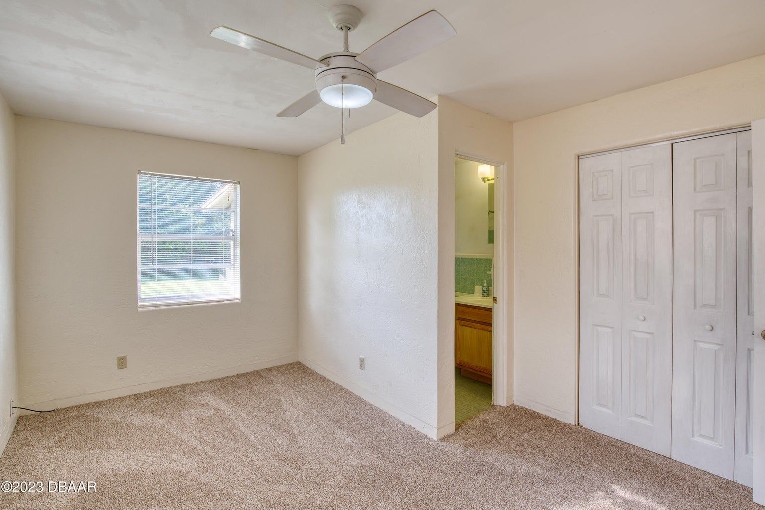 an empty bedroom with a ceiling fan and a window