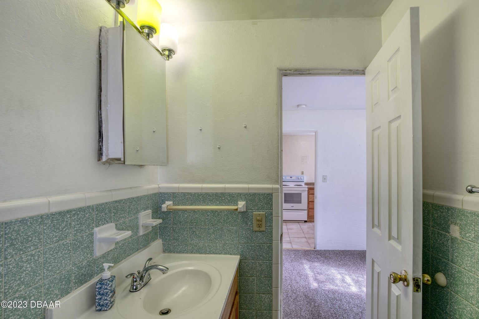 a bathroom with a sink and mirror and a door that is open