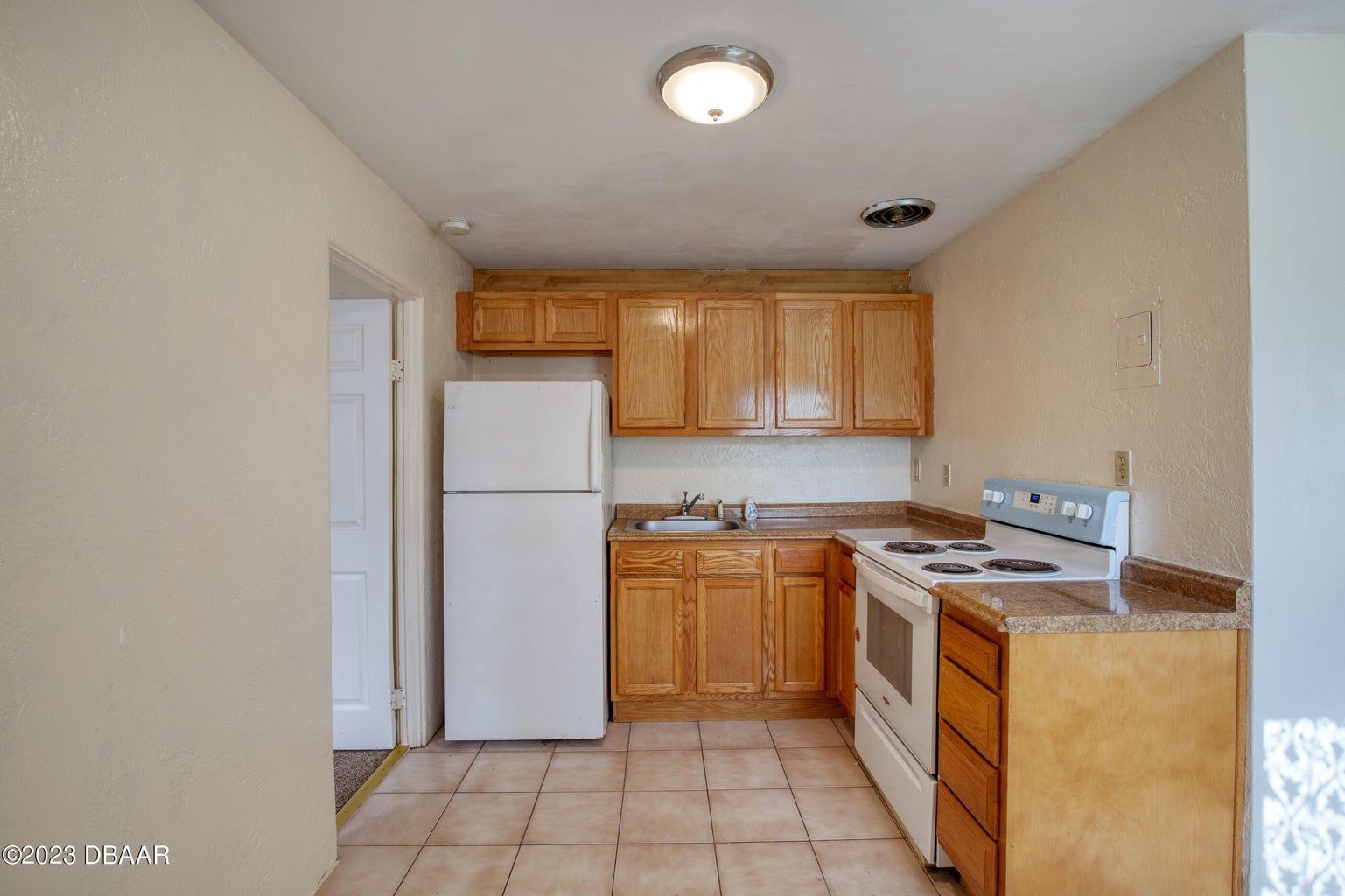 an empty kitchen with a white refrigerator and stove