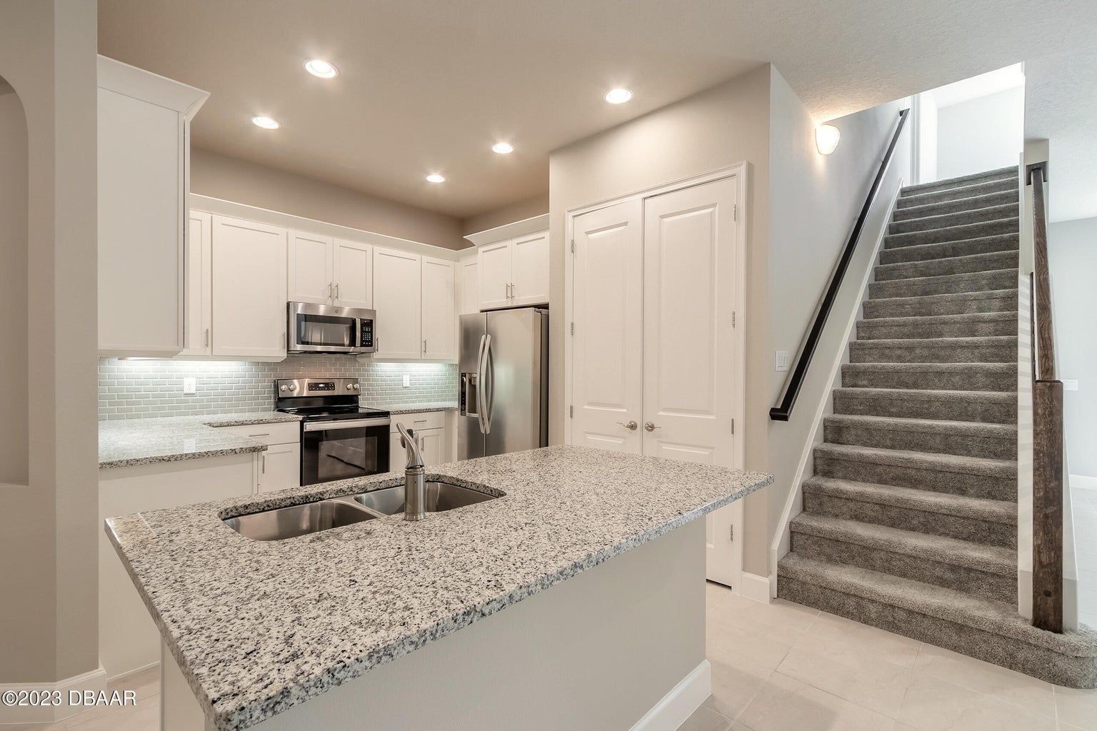 a kitchen with granite counter tops and stairs leading up to the second floor
