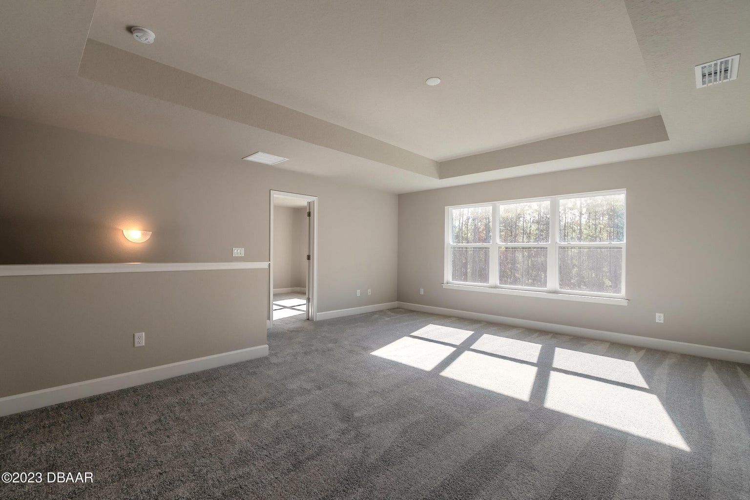 an empty room with a lot of windows and a gray carpet .