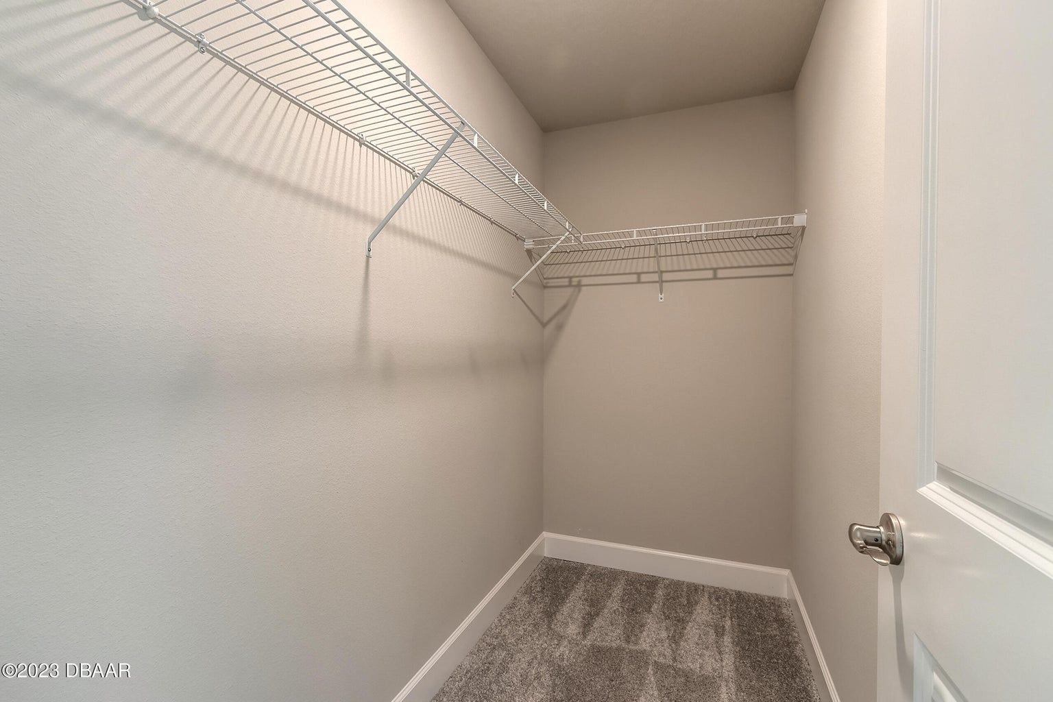 a walk in closet with a lot of shelves and a door .