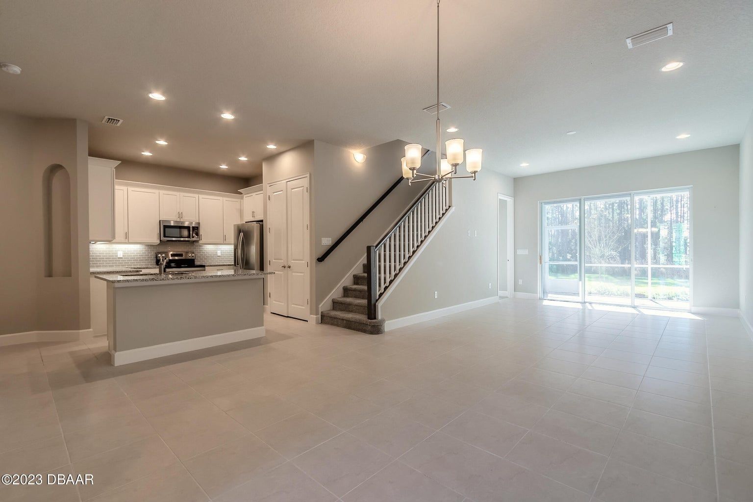 a large empty room with a kitchen and stairs