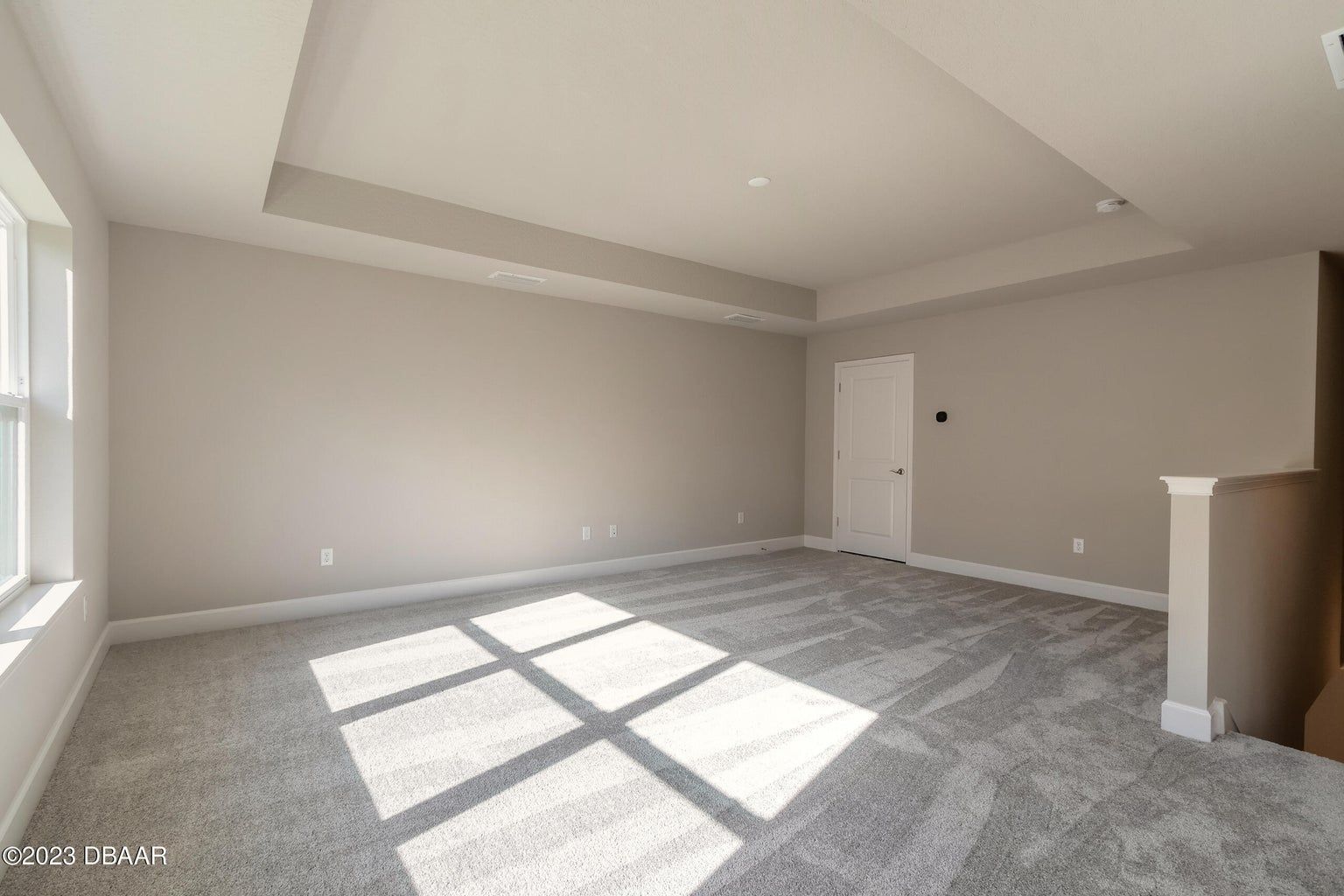 an empty living room with a carpeted floor and a window .