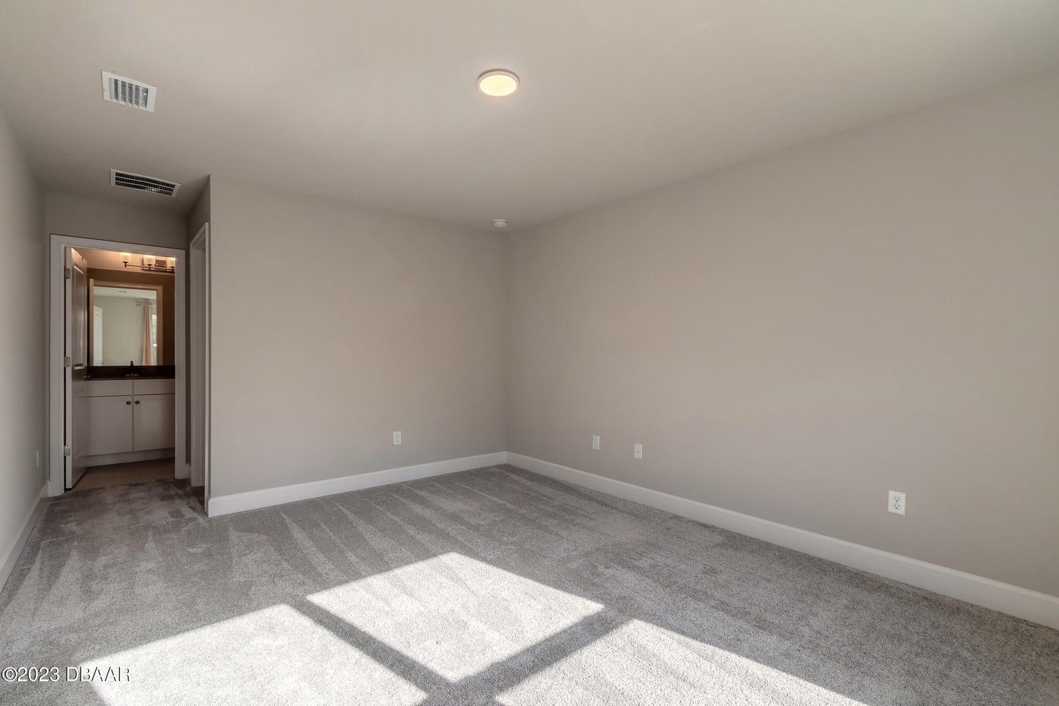 an empty bedroom with a carpeted floor and a bathroom .