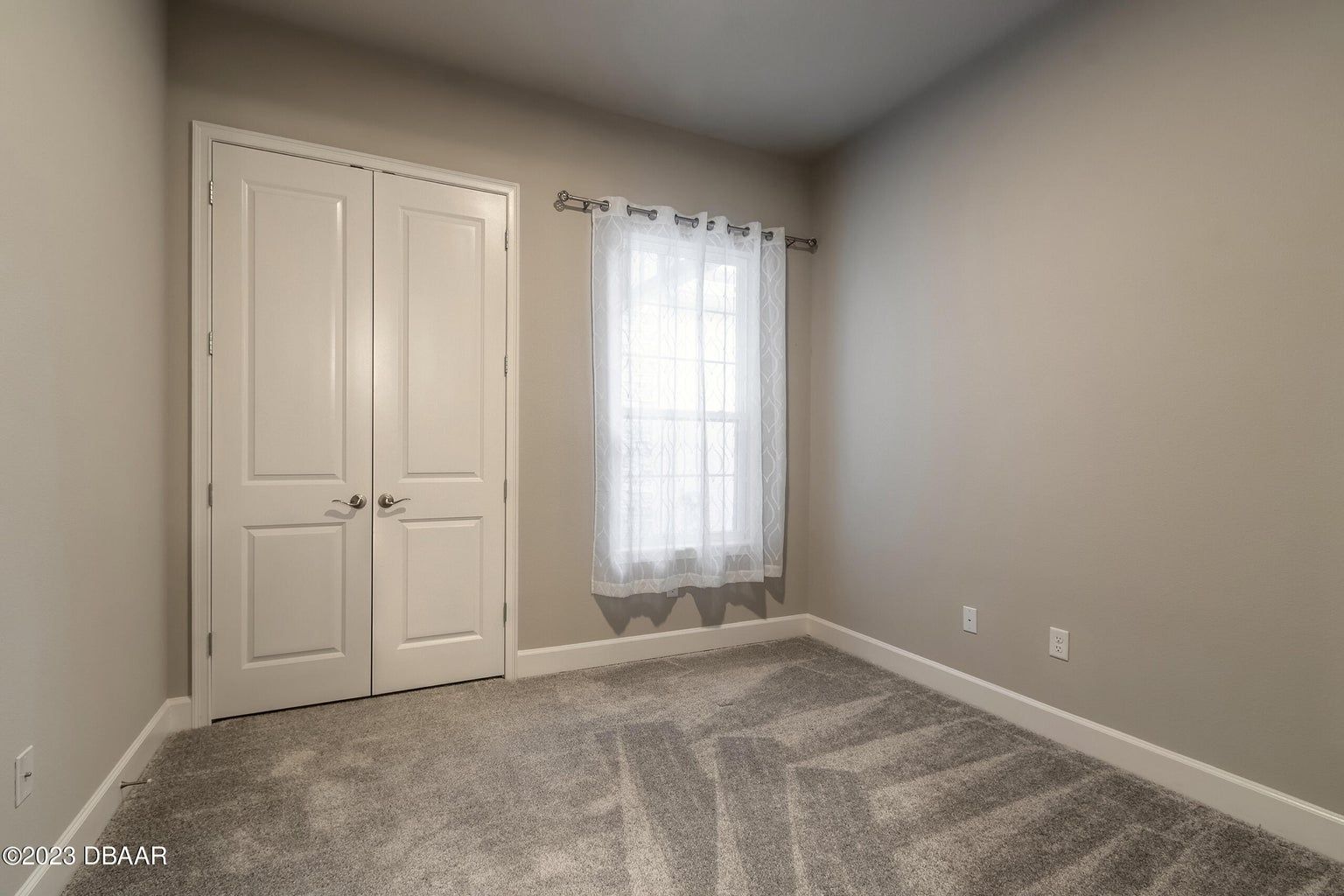 an empty bedroom with a carpeted floor and a window .