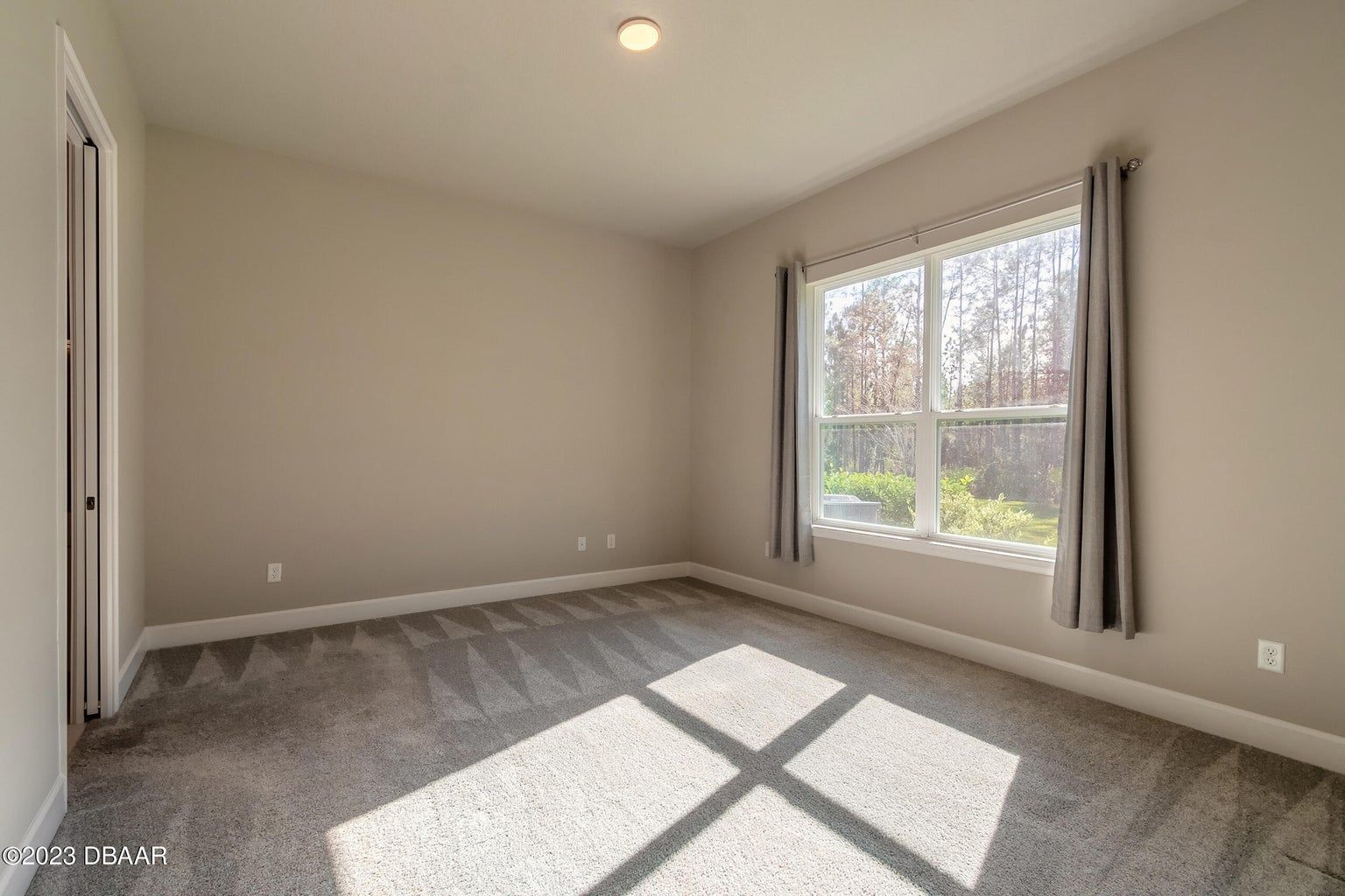 an empty bedroom with a large window and a carpeted floor .