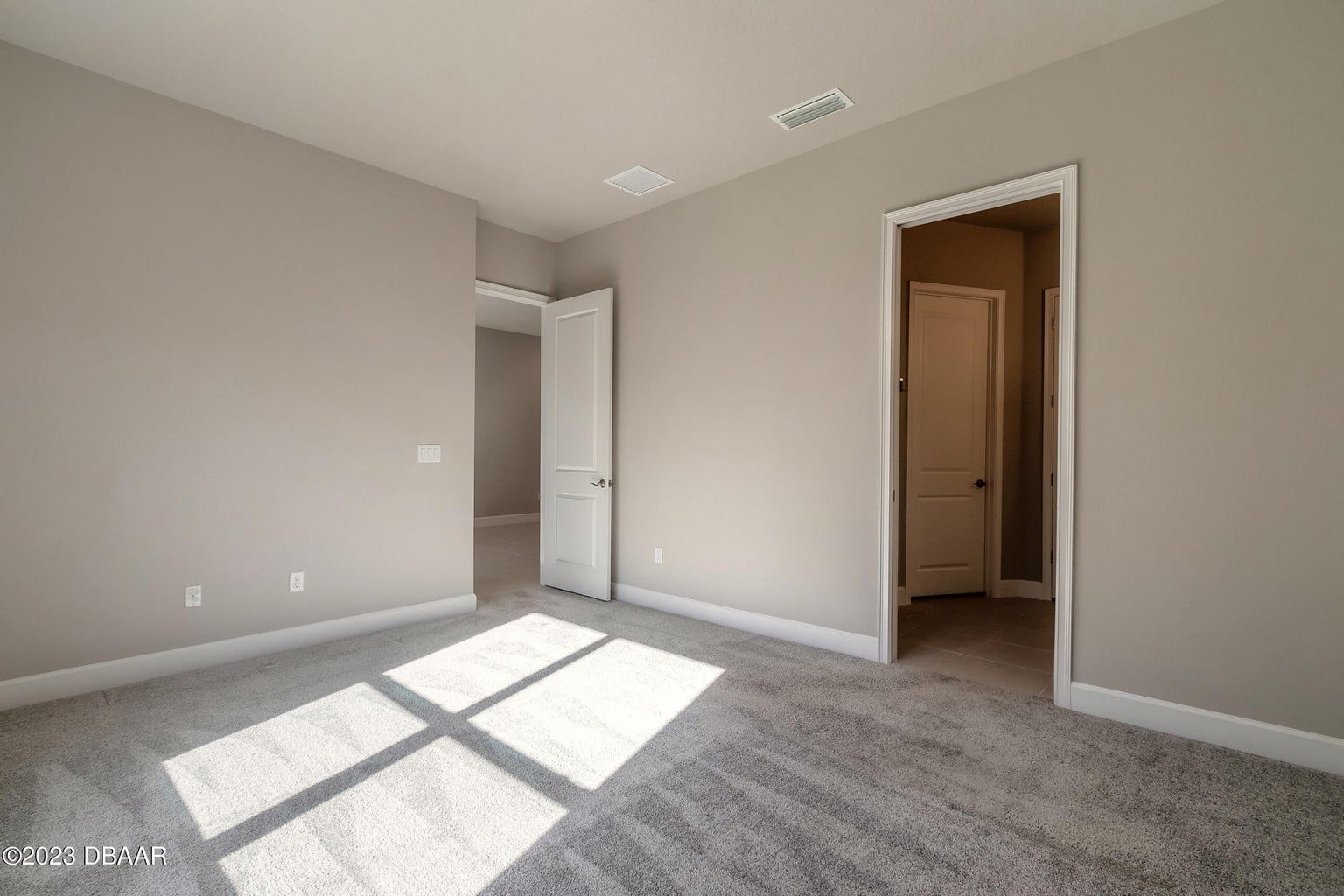 an empty bedroom with a carpeted floor and a window .