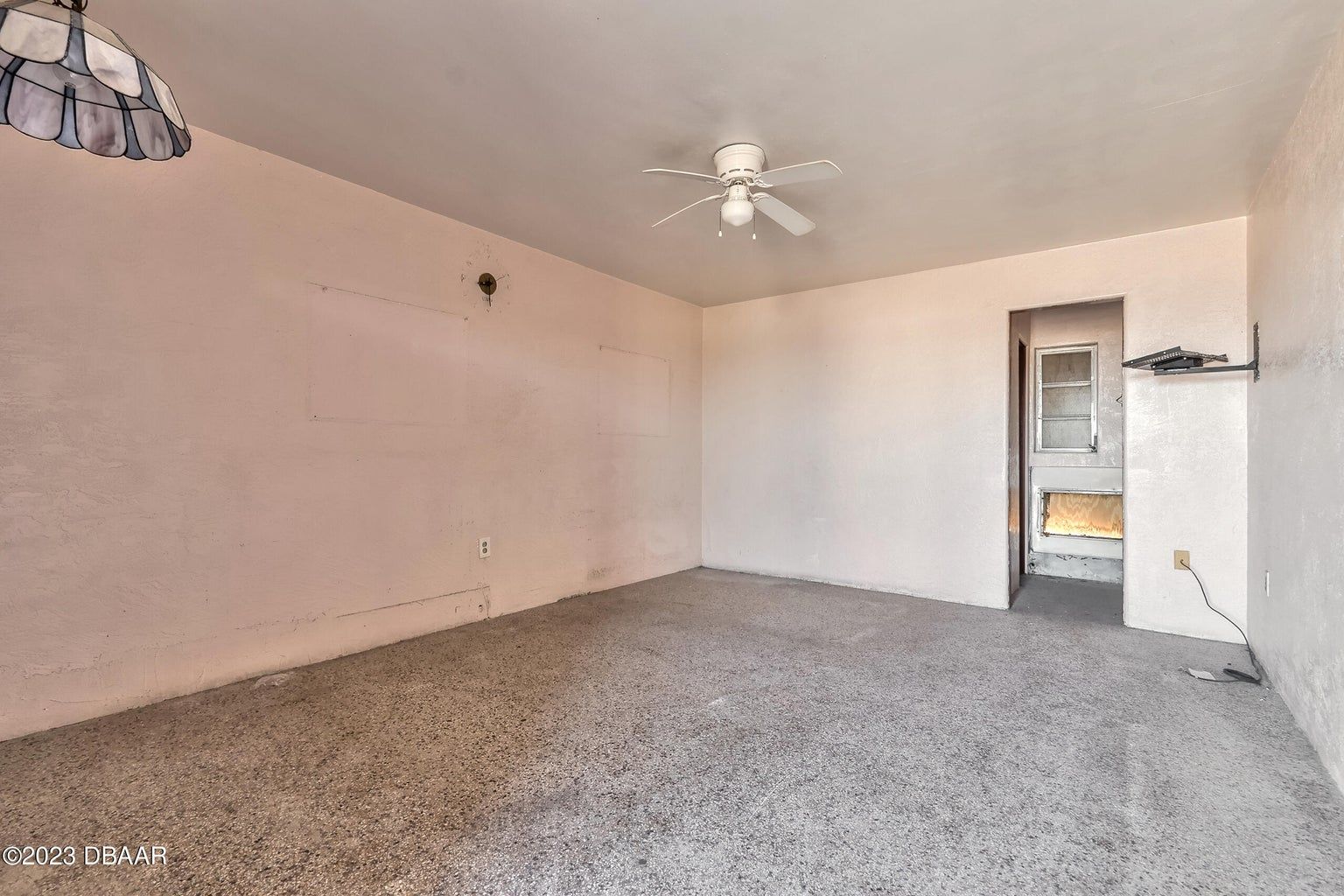 an empty room with a ceiling fan in the corner