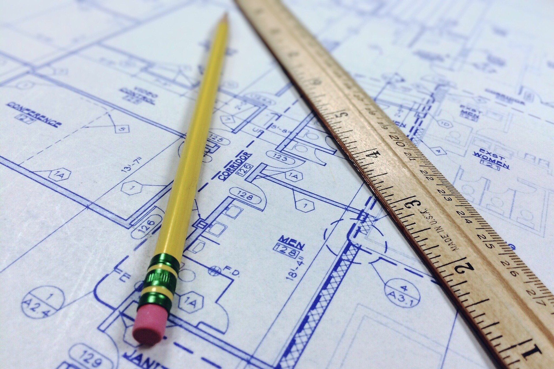 blueprints with a wooden pencil and wooden ruler on top.