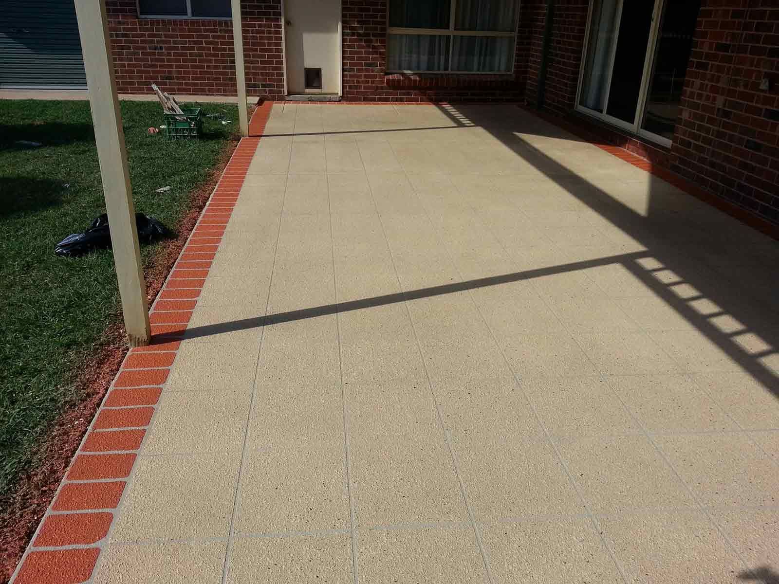 A Brick House With A Concrete Walkway Leading To It — Custom Concrete Finishes In Thurgoona, NSW