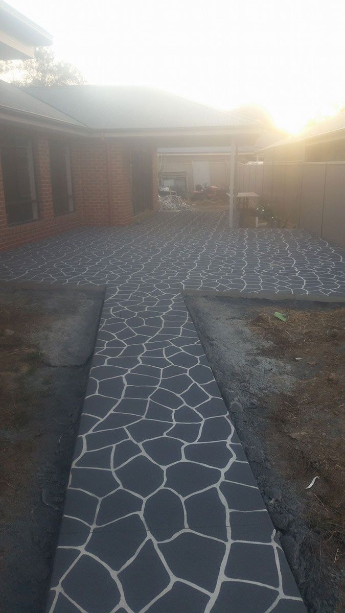 A Stone Walkway Leading To A House With A Sunset In The Background — Custom Concrete Finishes In Thurgoona, NSW