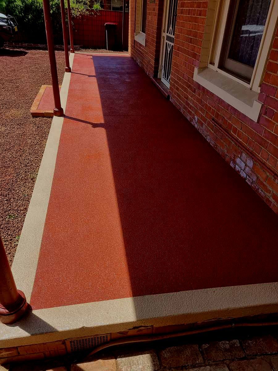 A Red And White Porch With A Brick Building In The Background — Custom Concrete Finishes In Thurgoona, NSW