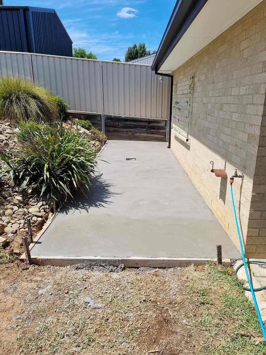 A Concrete Walkway Is Being Built In The Backyard Of A House — Custom Concrete Finishes In Thurgoona, NSW