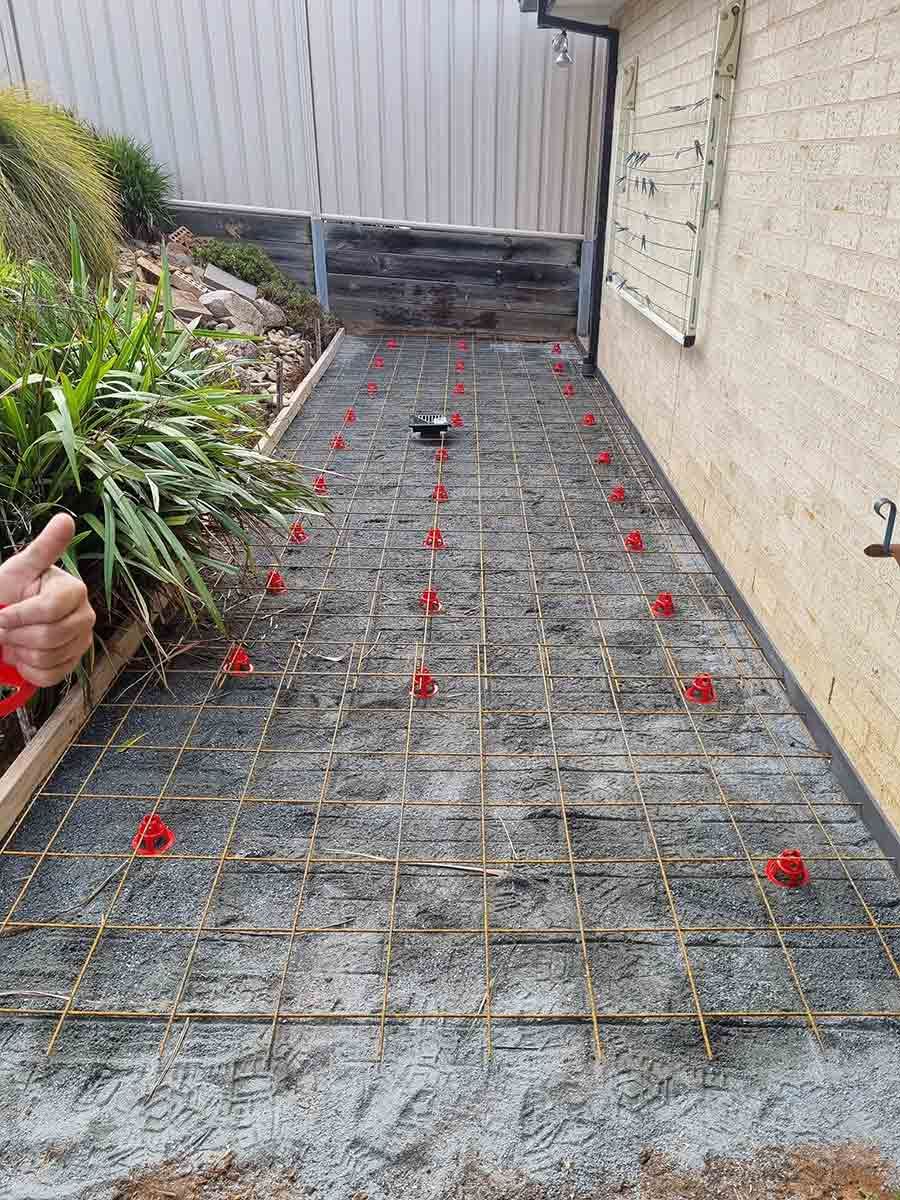 A Person Is Laying Concrete On A Sidewalk Next To A House — Custom Concrete Finishes In Thurgoona, NSW