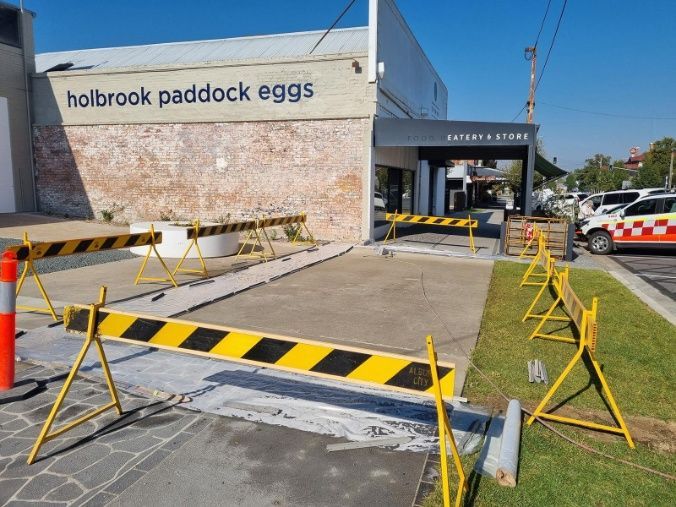 A Yellow And Black Barrier Is Sitting In Front Of A Building — Custom Concrete Finishes In Thurgoona, NSW