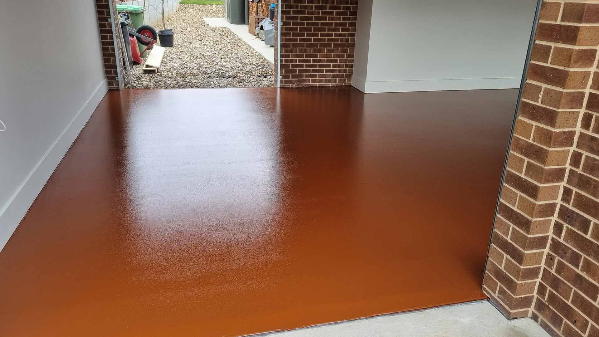 A Garage With A Brick Wall And A Red Floor — Custom Concrete Finishes In Thurgoona, NSW