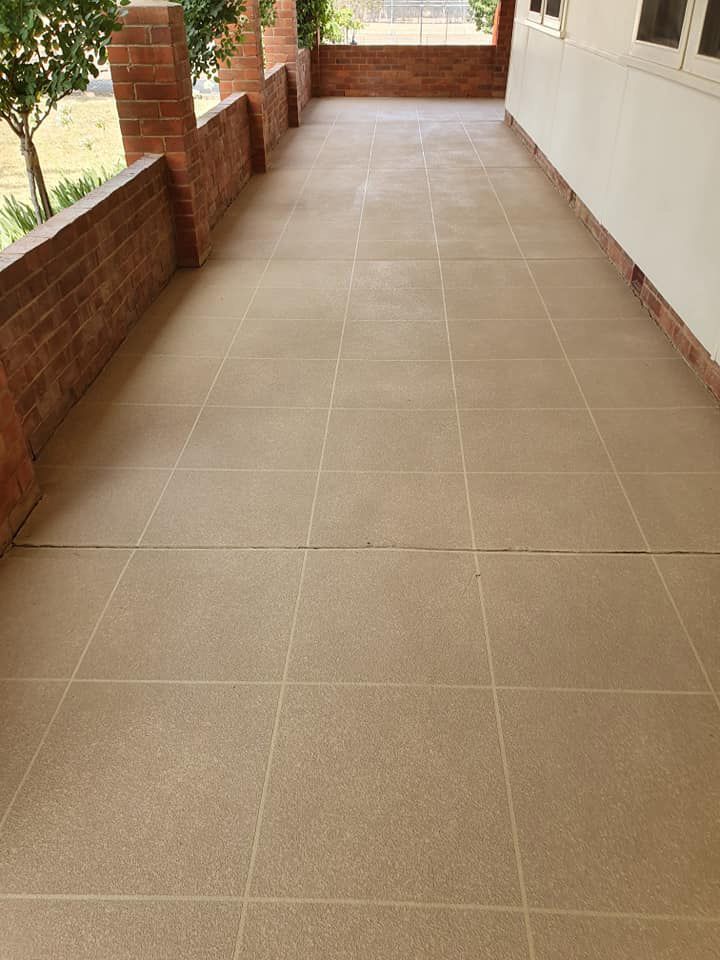 A Tiled Floor On A Porch Next To A Brick Wall — Custom Concrete Finishes In Thurgoona, NSW