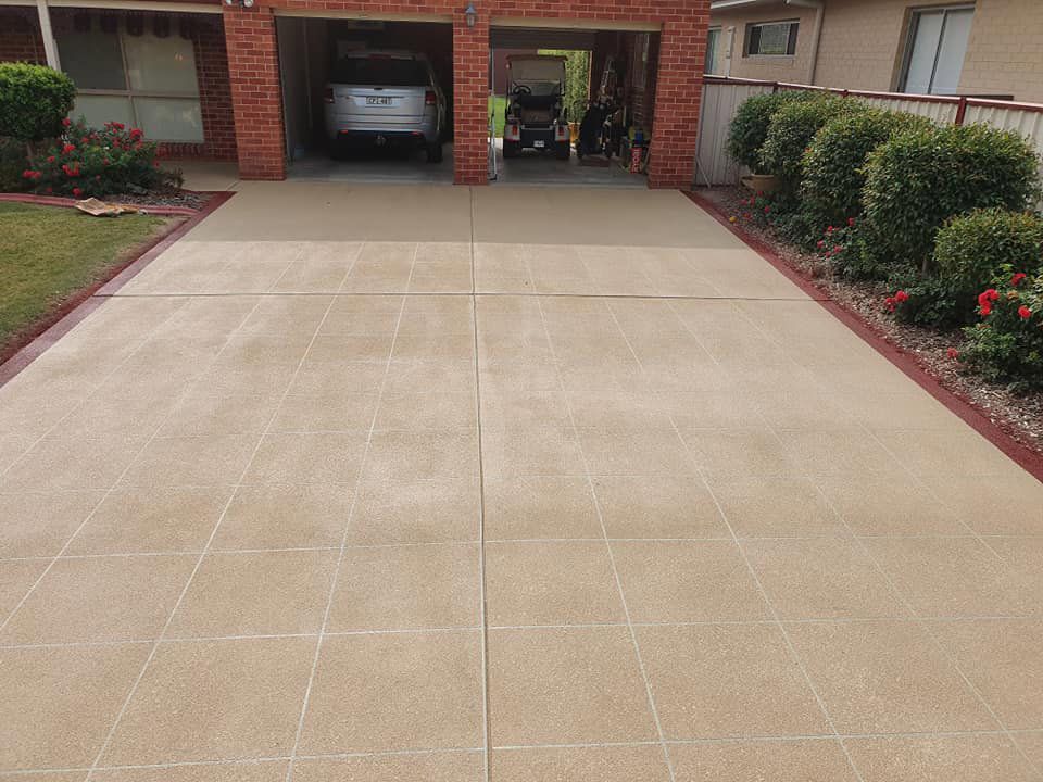 A Car Is Parked In A Garage Next To A Driveway — Custom Concrete Finishes In Thurgoona, NSW