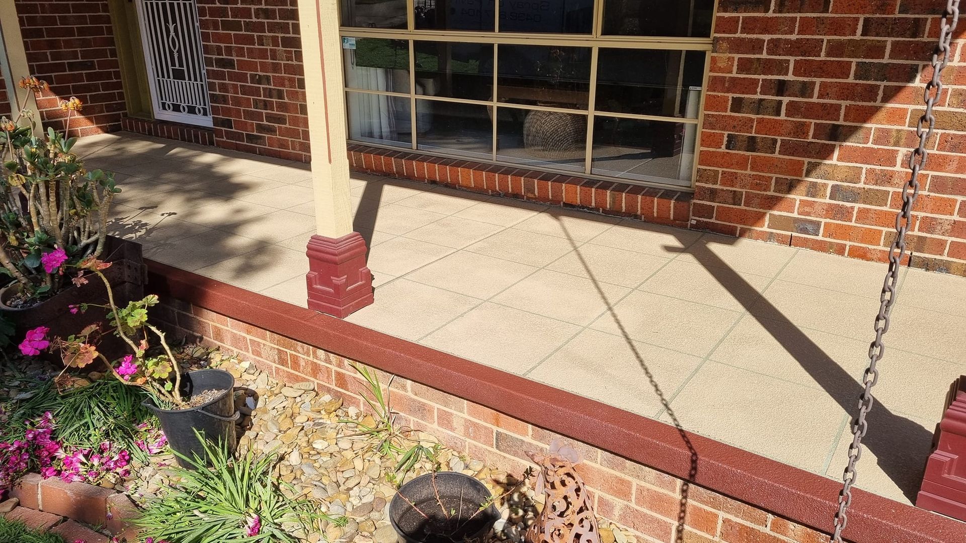 A Concrete Floor Is Being Painted In A Driveway Next To A Brick Wall — Custom Concrete Finishes In Thurgoona, NSW